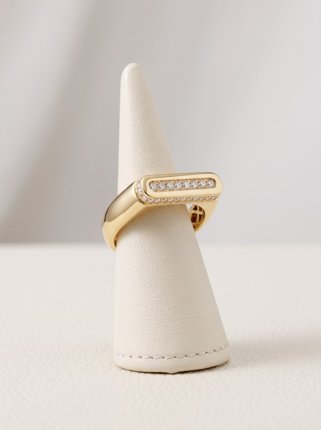 Yellow gold diamond bar dress ring displayed on ivory stand