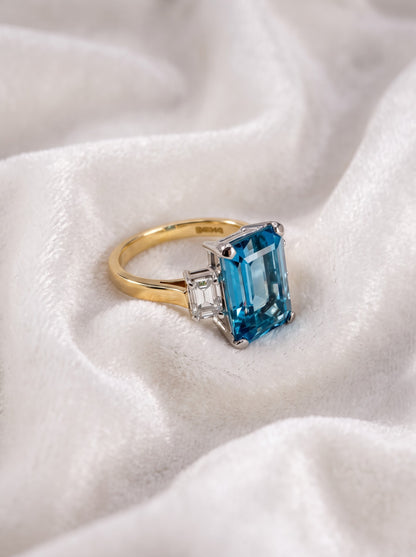Side profile of aquamarine and diamond trilogy ring on ivory fabric