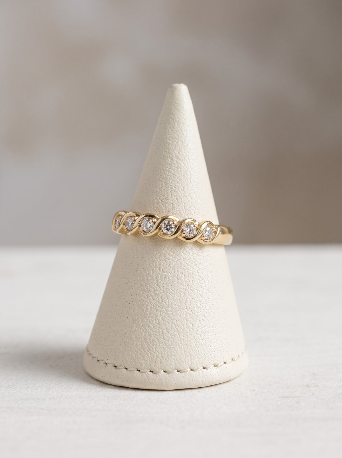 Seven-stone diamond twist ring in 18ct yellow gold displayed on stand